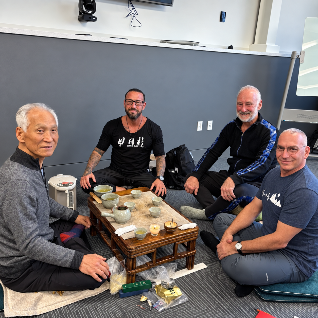 Four people gathered around a tea table, sharing a quiet moment together.